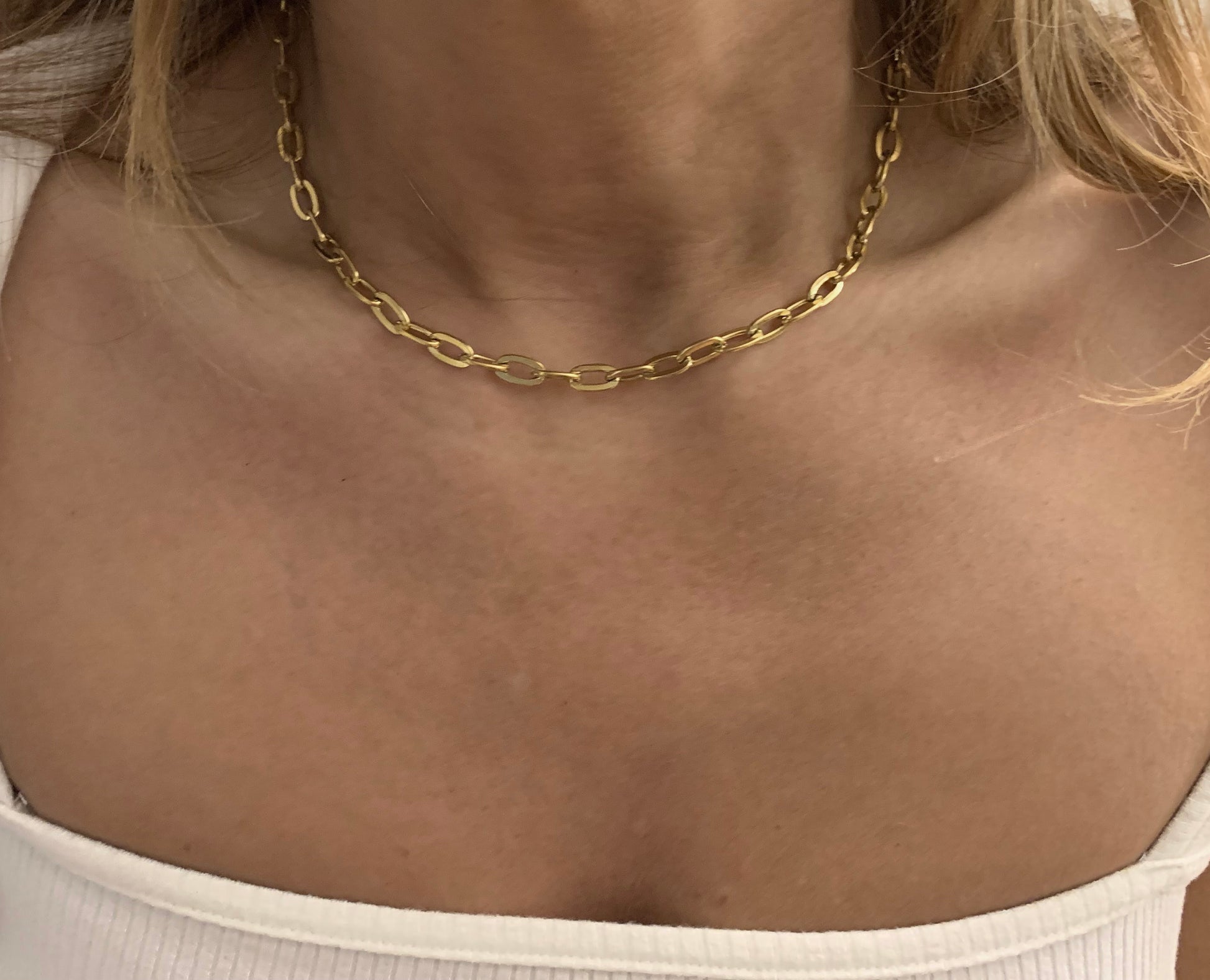 Gold chain necklace on a person wearing a white top