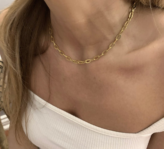 Gold chain necklace on a person wearing a white top