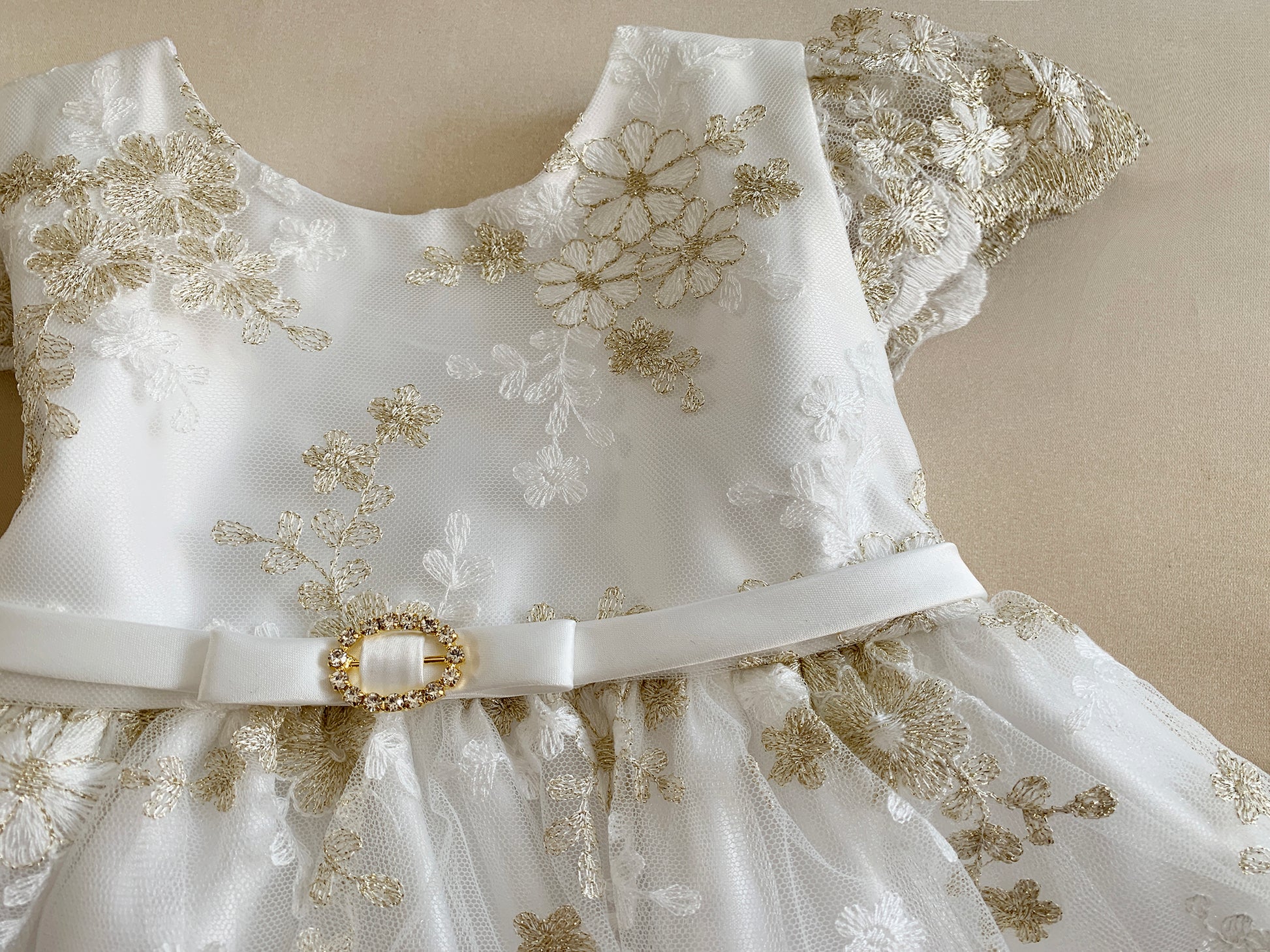 White dress with gold floral embroidery on a beige background