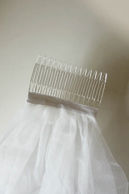 Comb with a white tulle veil on a neutral background
