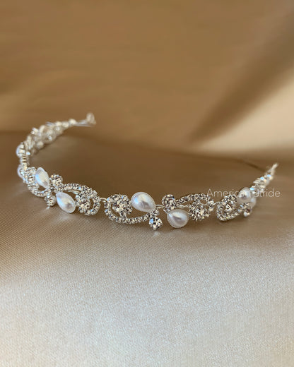 Silver tiara with pearls on a beige fabric background