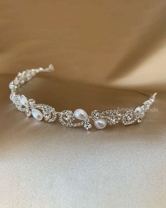 Silver tiara with pearls on a beige fabric background