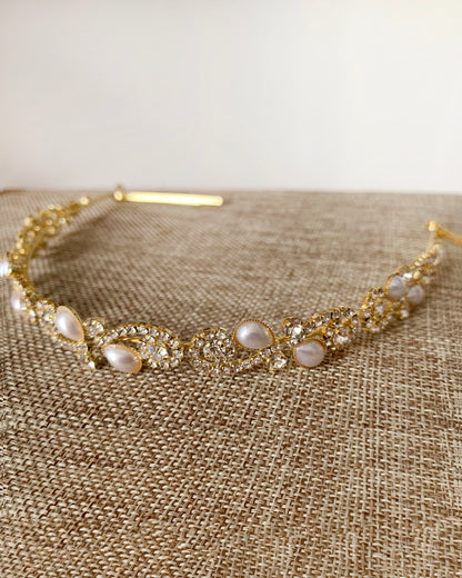 Gold headband with pearls and rhinestones on a textured fabric background