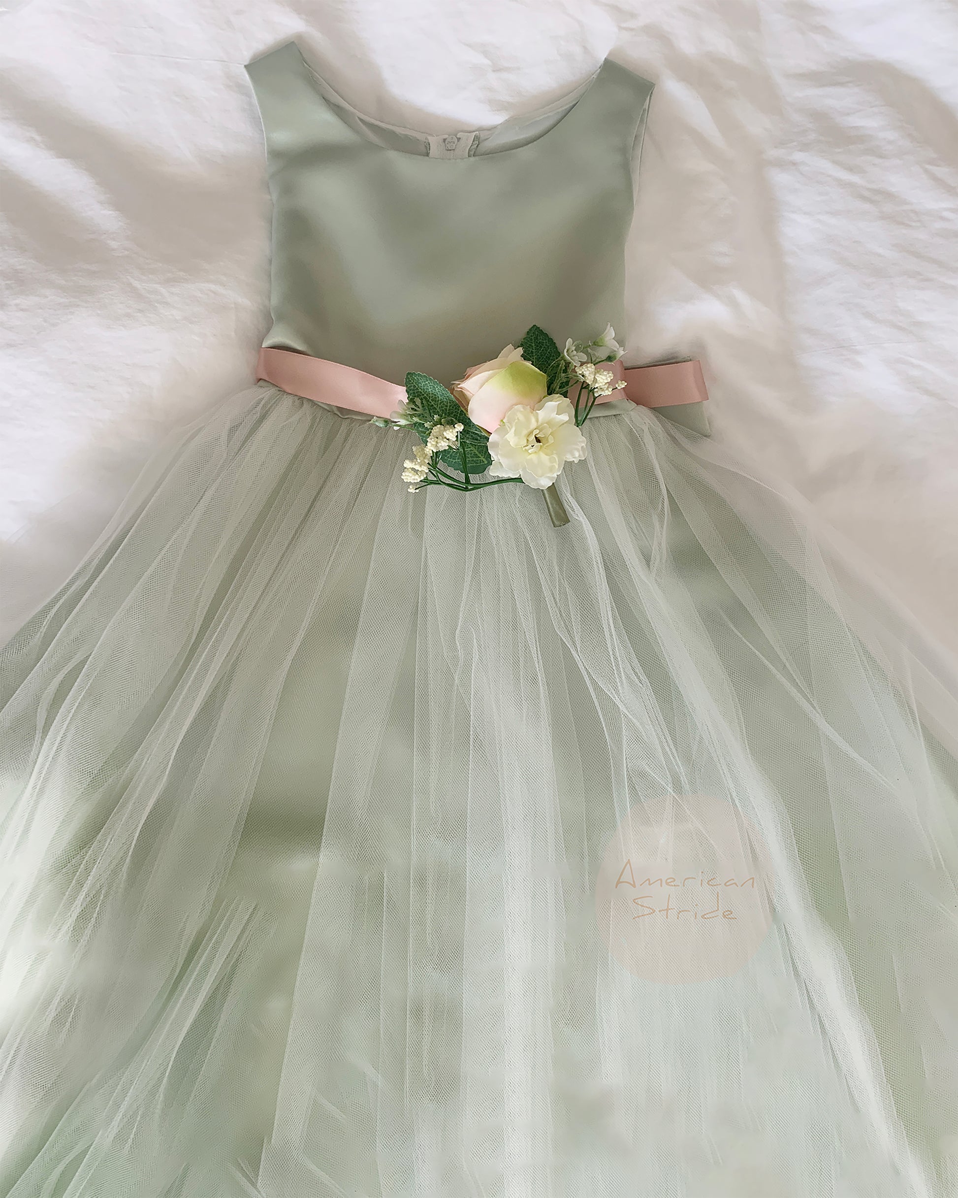 sage dress with a floral sash on a white fluffy surface
