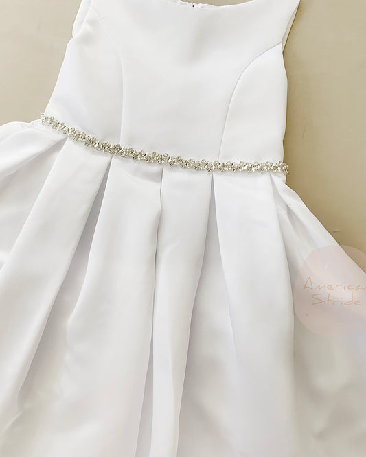 White dress with a decorative belt on a neutral background