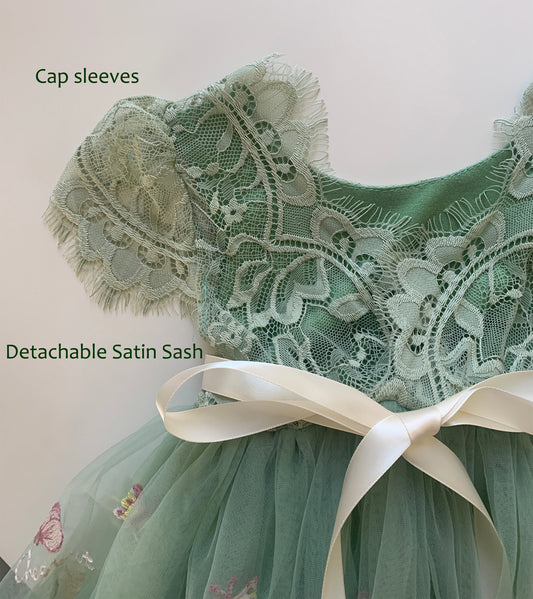 Green lace dress with cap sleeves and detachable satin sash on a plain background