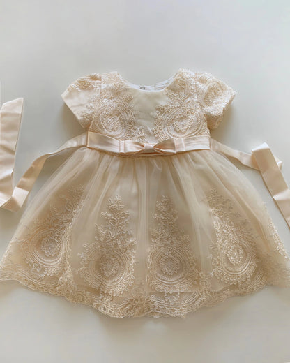 champagne lace dress with a bow on a light background