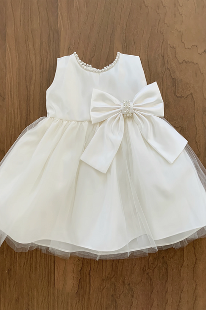 Ivory dress with a large bow on a wooden surface