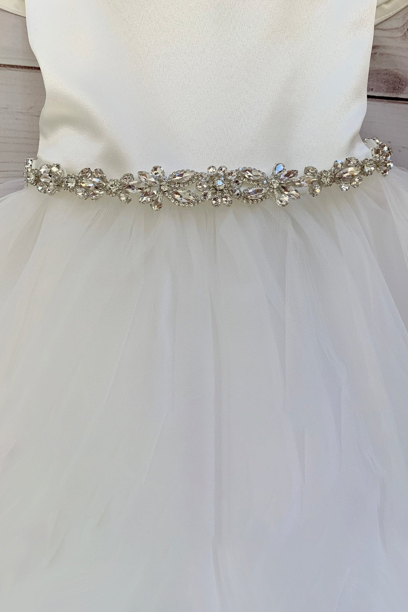 White wedding dress with a decorative  clear rhinestone belt on a wooden background