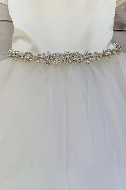 White wedding dress with a decorative  clear rhinestone belt on a wooden background