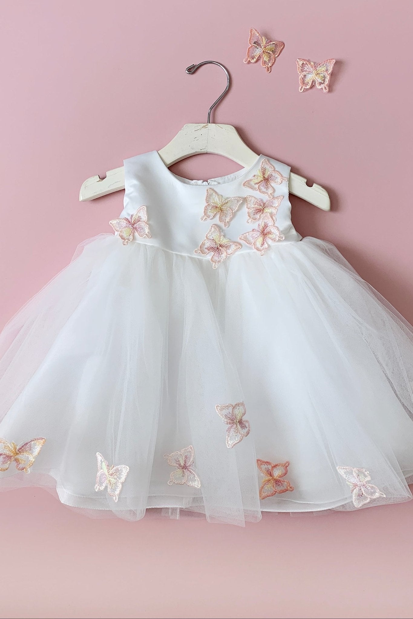 White dress with butterfly embroidery on a pink background