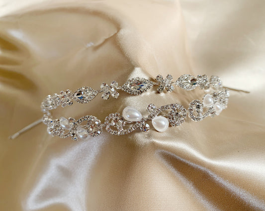 Silver hair vine with crystals and pearls on a beige satin background