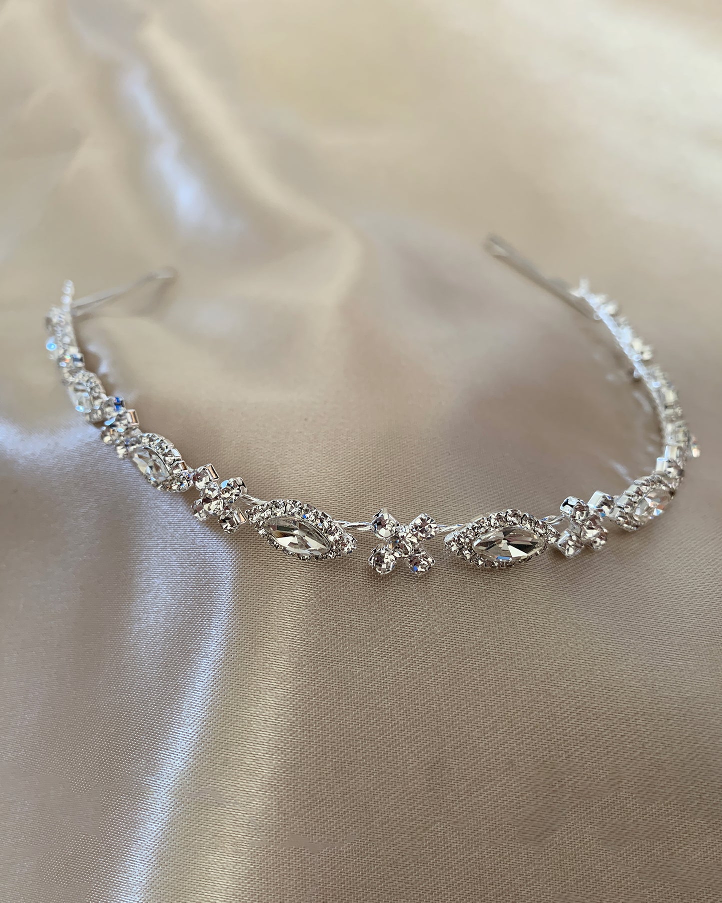 Silver head band with clear stones on a beige fabric background