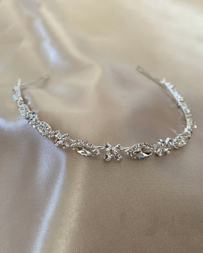 Silver head band with clear stones on a beige fabric background