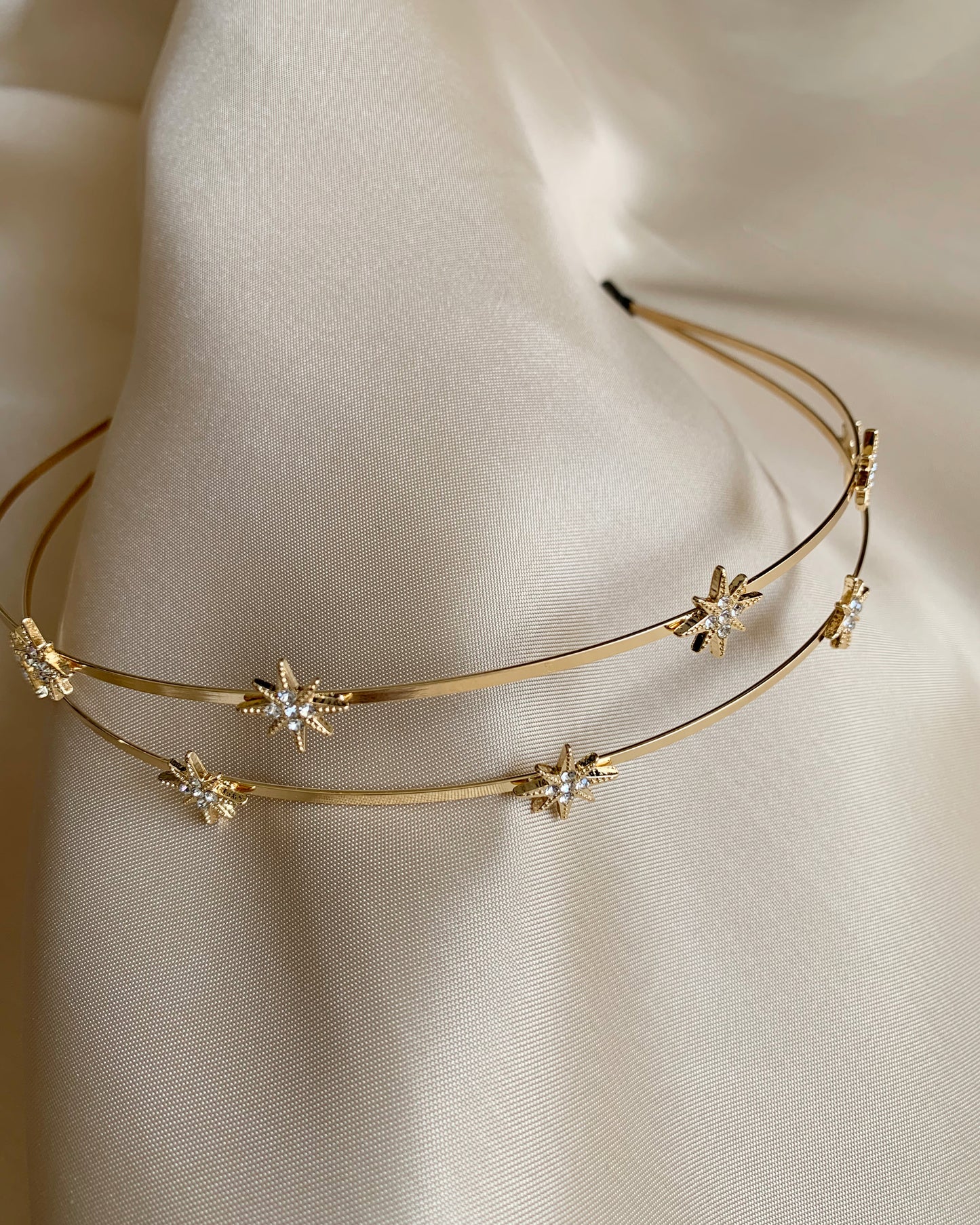 Gold headband with star shaped and rhinestone on a neutral background