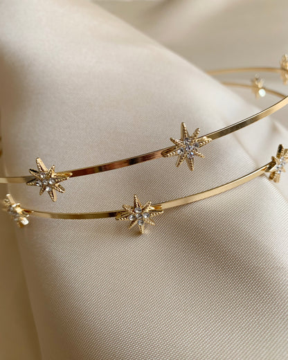 Gold headband with star-shaped embellishments on a soft beige background