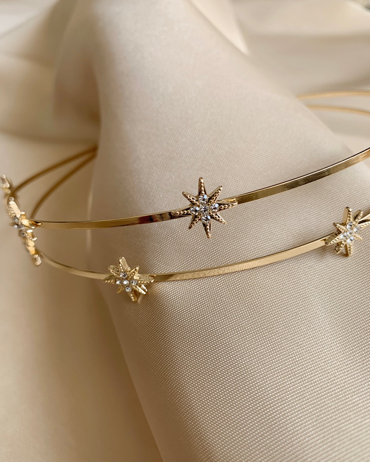 Gold headband with star-shaped embellishments on a beige fabric background