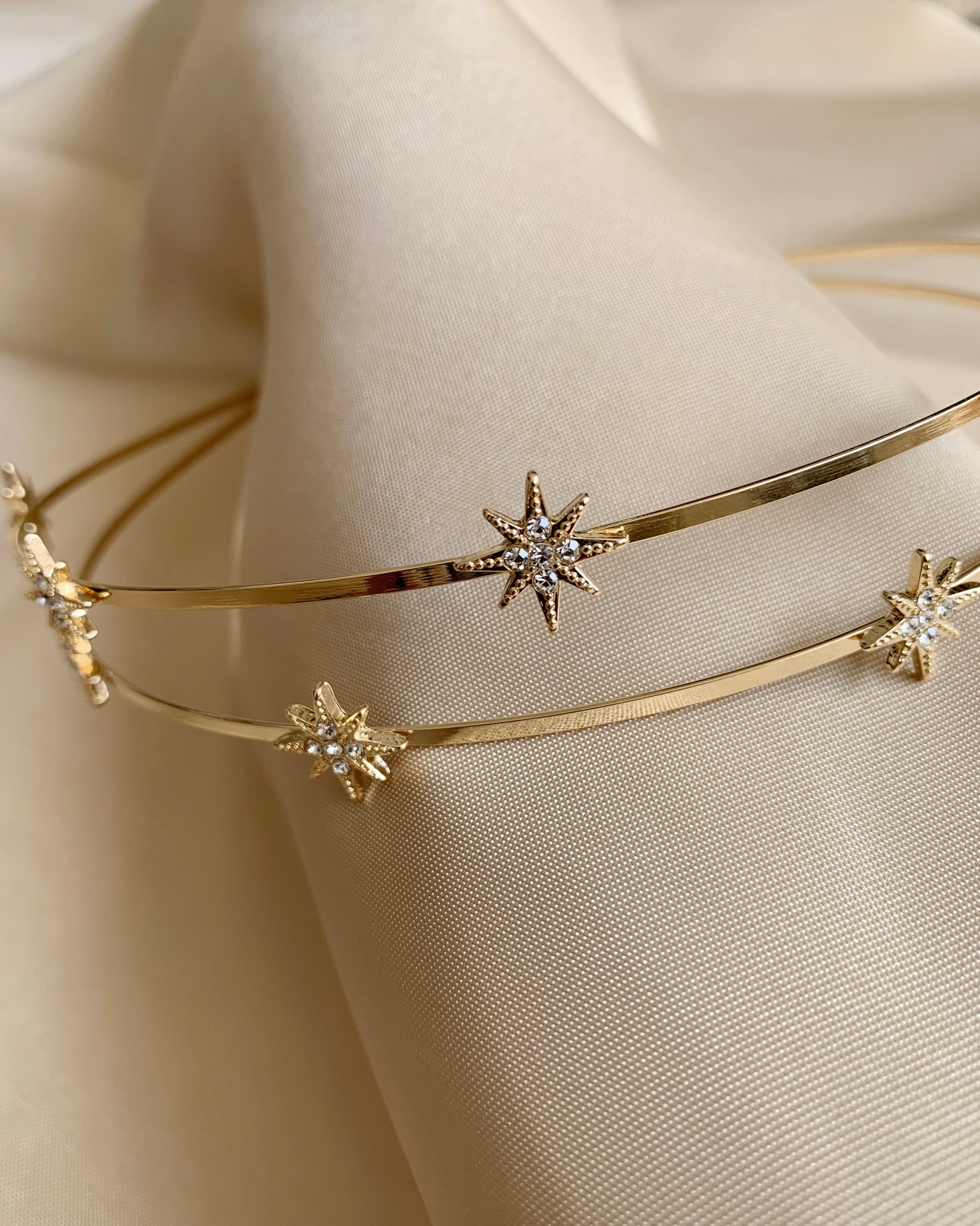 Gold headband with star-shaped embellishments on a beige fabric background