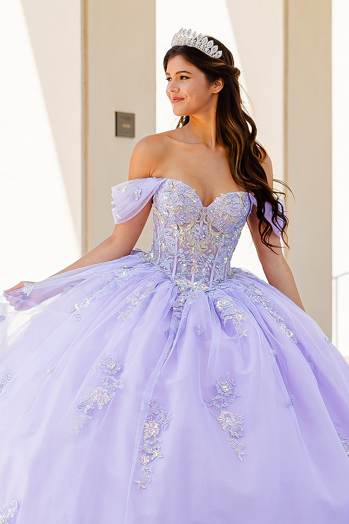 Quinceanera | Lilac Two-Tone See-Through Shimmering Sequins and 3D flowers Bodice Ballgown - front view of woman wearing dress and crown smiling of into the distance