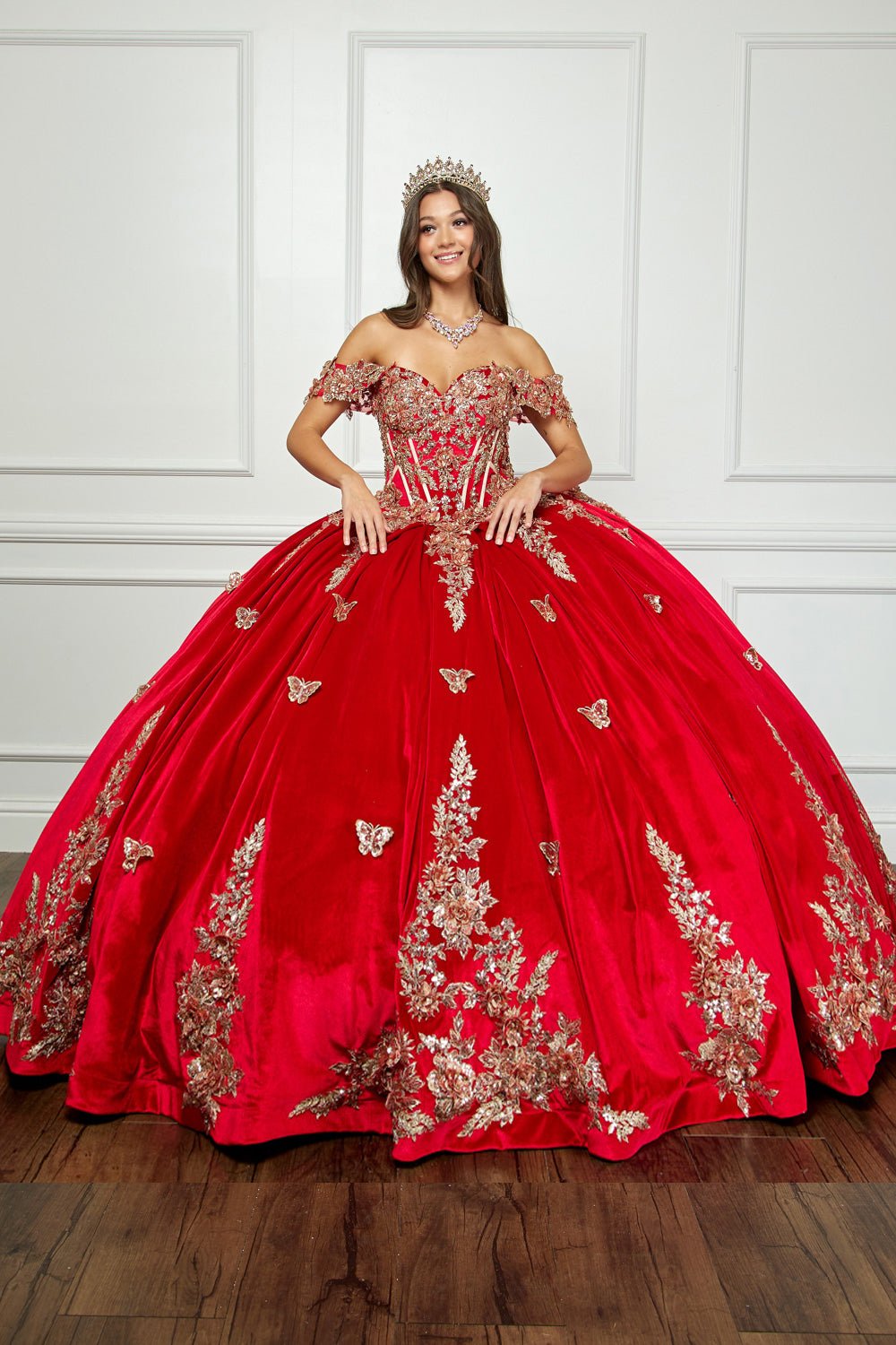 a girl wearing Red Quinceanera dress - shoulder Velvet Sweetheart Gold Sequin sequin butterfly floral Ballgown with Sweep train - front view of woman wearing dress and crown