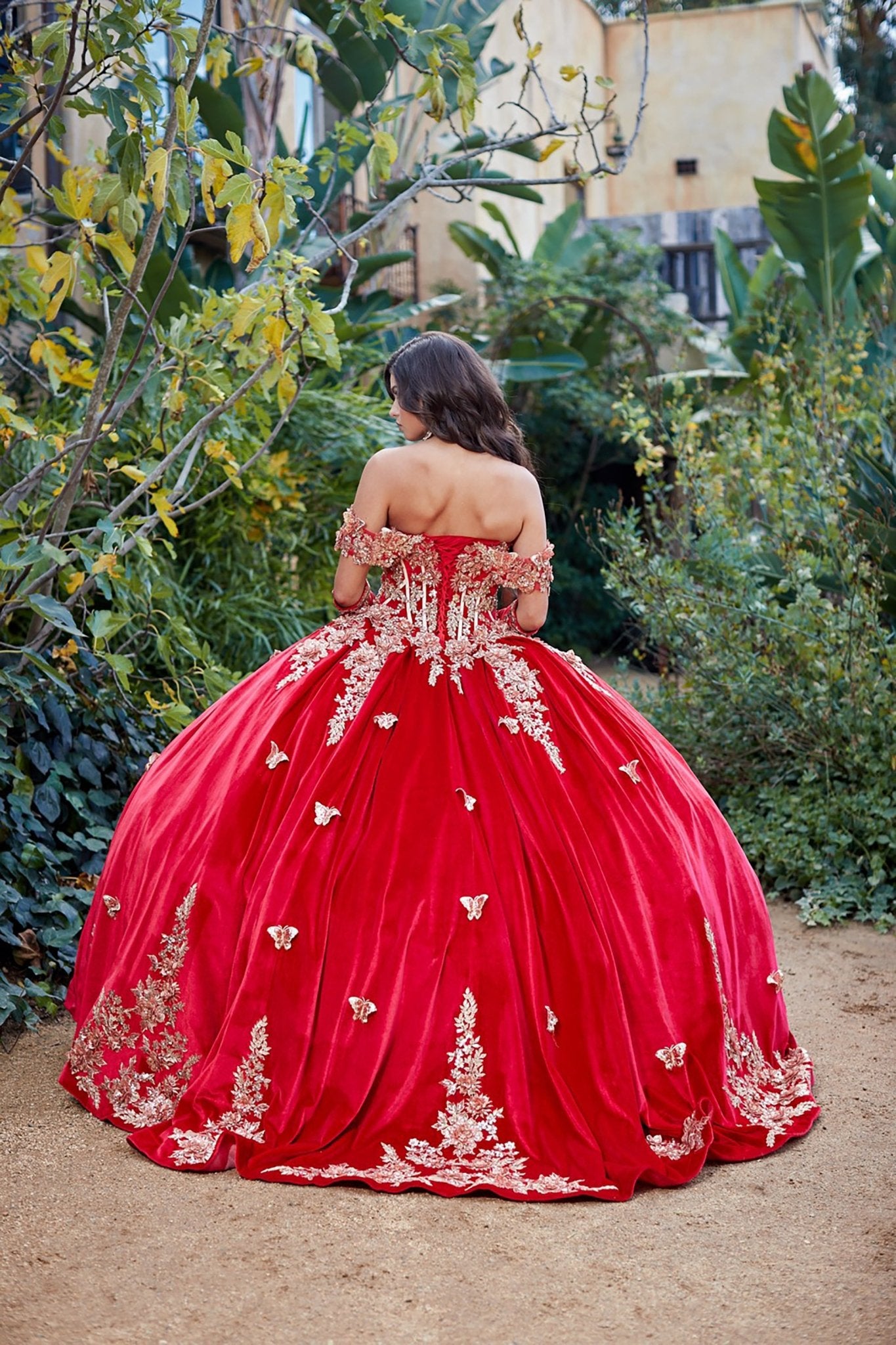 Red ball gown with gold embroidery in a garden setting