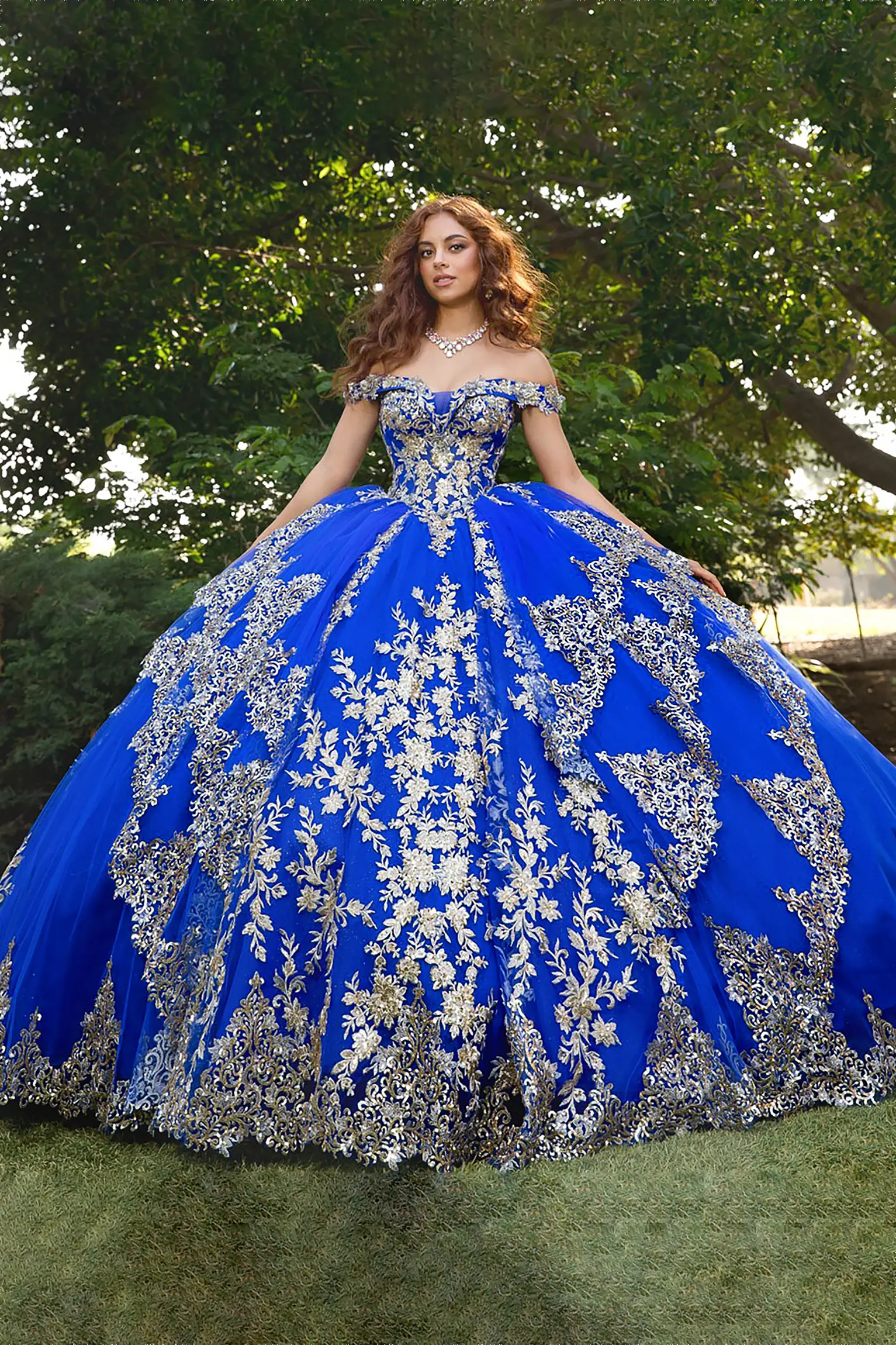 Woman wearing a sweet heart off the shoulder royal blue quinceanera ball gown with silver embroidery 
