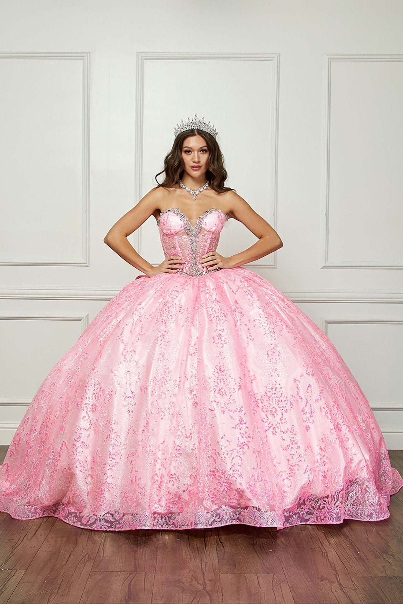 Pink quinceanera dress with lace details on a wooden floor.