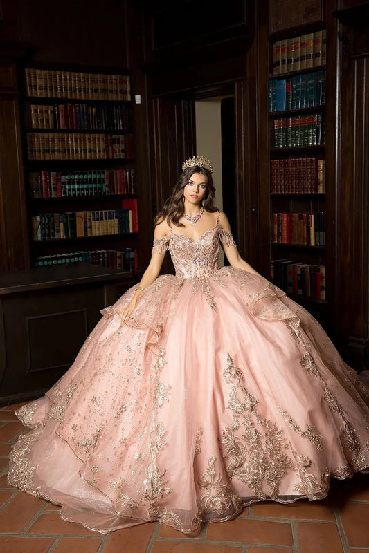 A girl in a rose gold quinceanera ball gown with intricate details standing in a room with bookshelves.