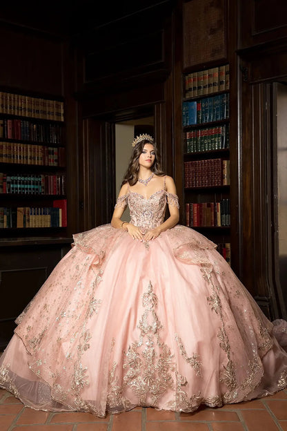 A girl in a rose gold ball gown with gold embroidery standing in a library.