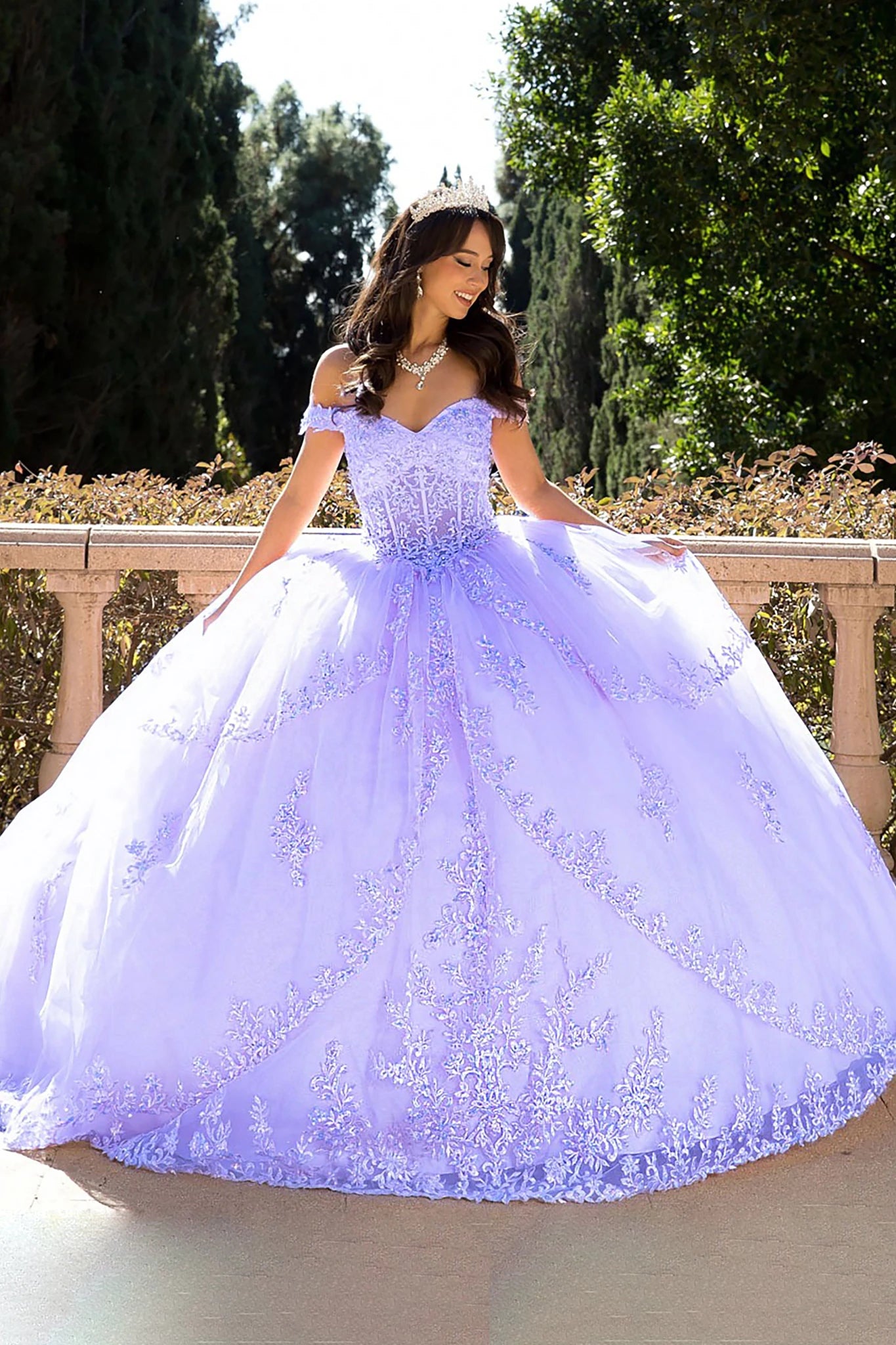 Woman in a lilac ball gown standing outdoors with greenery in the background