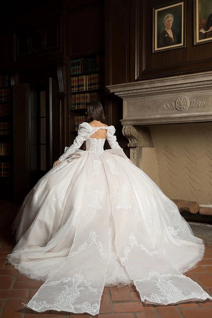 White wedding gown with long sleeves in a room with a fireplace and bookshelves.