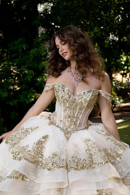 Model wearing ivory glitter tulle ball gown with sweetheart neckline and gold embellished corset.