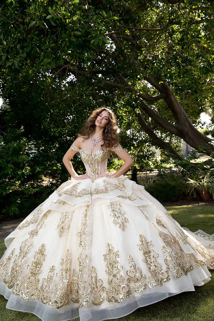 Woman posing in ball gown with sweetheart neckline, lace-up corset, and ornate gold appliqué in a garden.