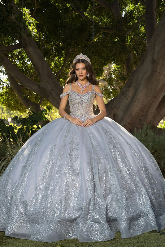 Woman in a sparkling silver ball gown standing outdoors with trees in the background