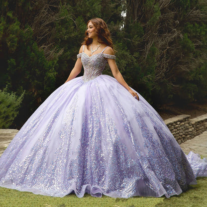 Woman in a sparkling purple gown standing outdoors with greenery in the background