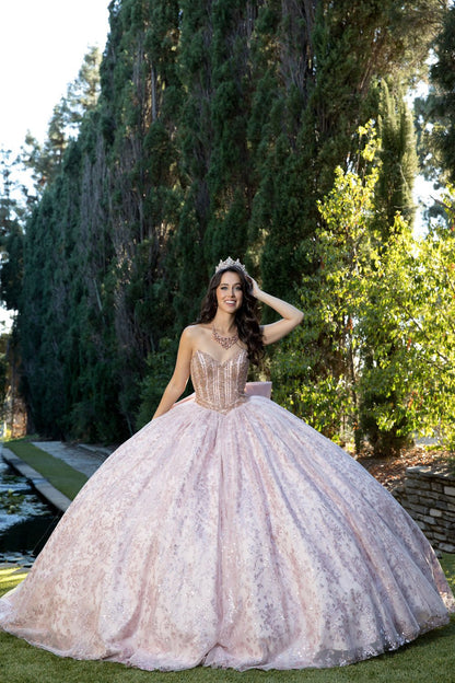 Woman in a pink quinceañera dress standing outdoors with trees in the background