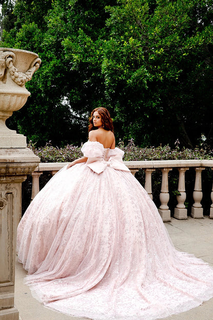 Woman in a pink quince dress standing outdoors with greenery in the background