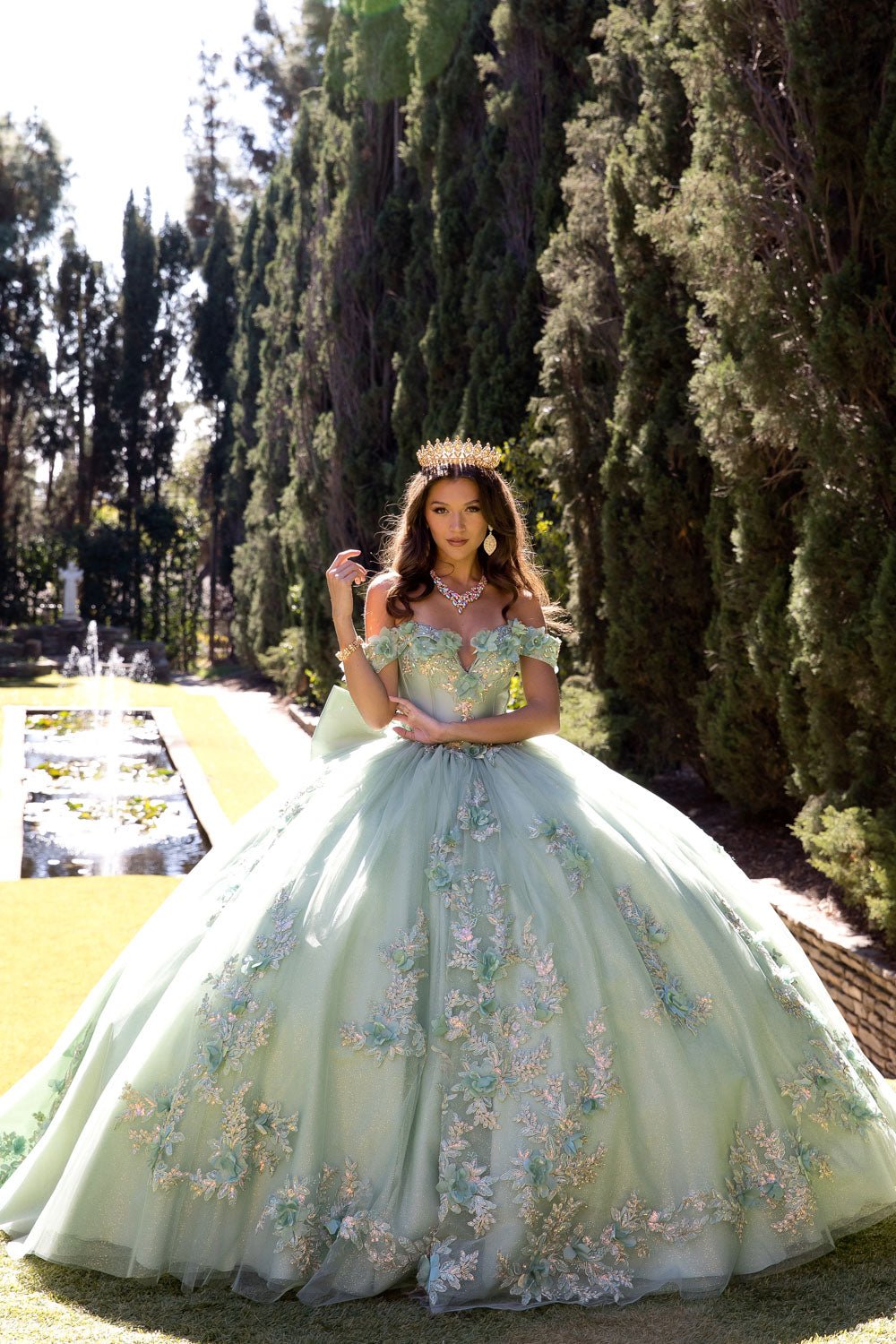 Woman in a floral dress standing outdoors with trees and a garden in the background