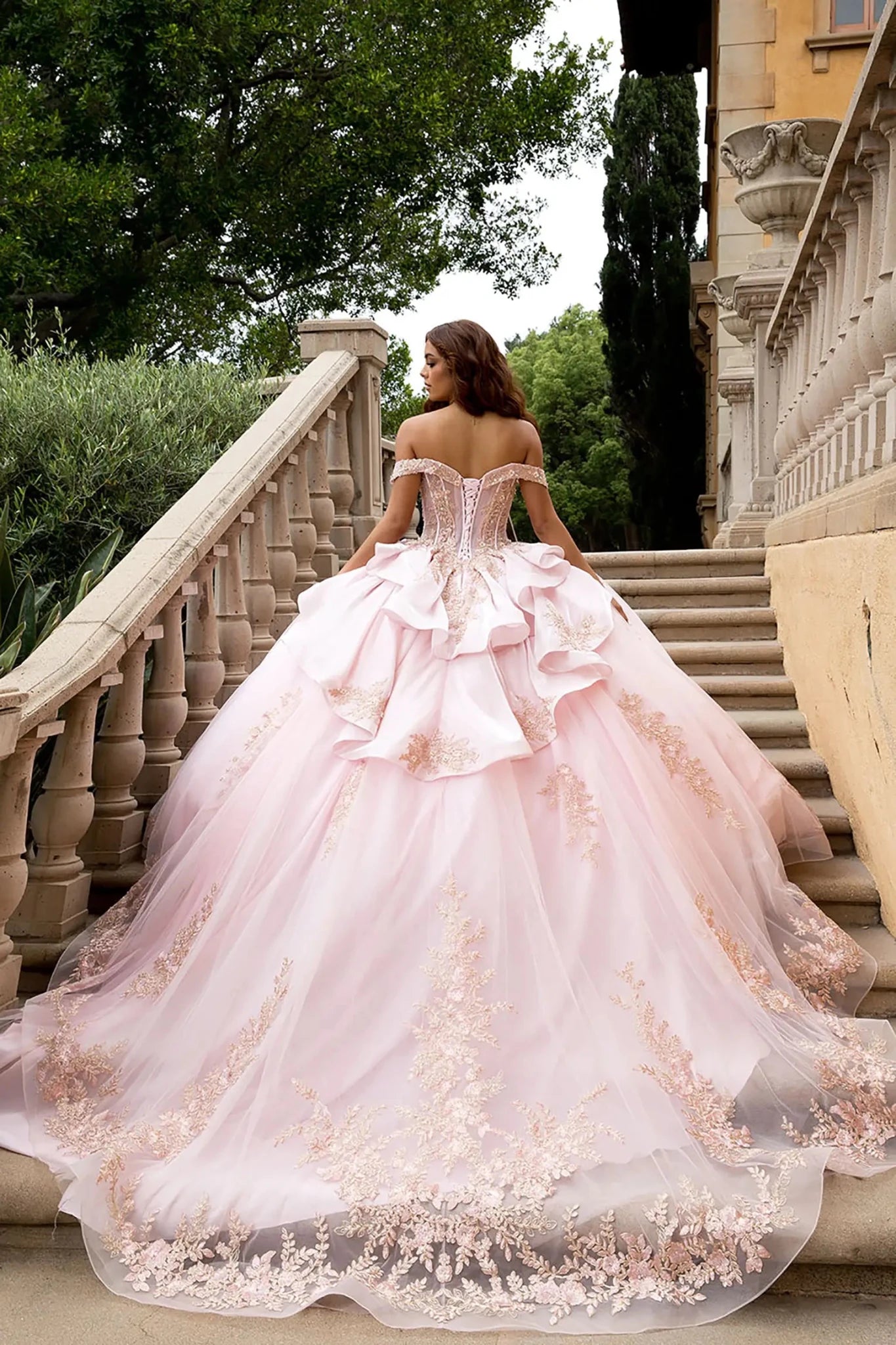 Back view Posed on a grand stone staircase with a classical villa background, the image highlights the massive scale of the glitter tulle ball gown skirt and the intricate rose gold floral lace embroidery cascading toward the hem.
