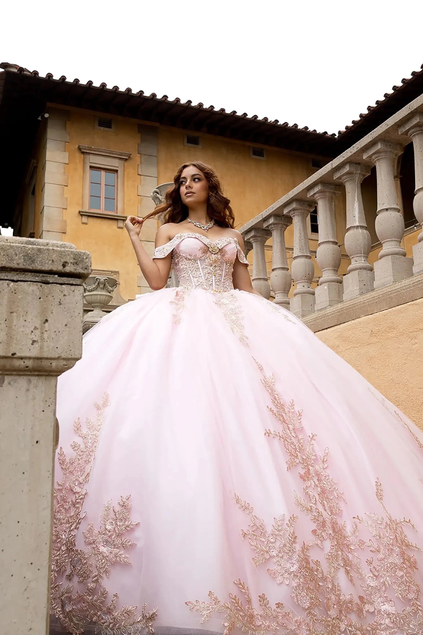 he model is wearing a matching rhinestone statement necklace, set against a luxurious architectural backdrop with classical balustrades.