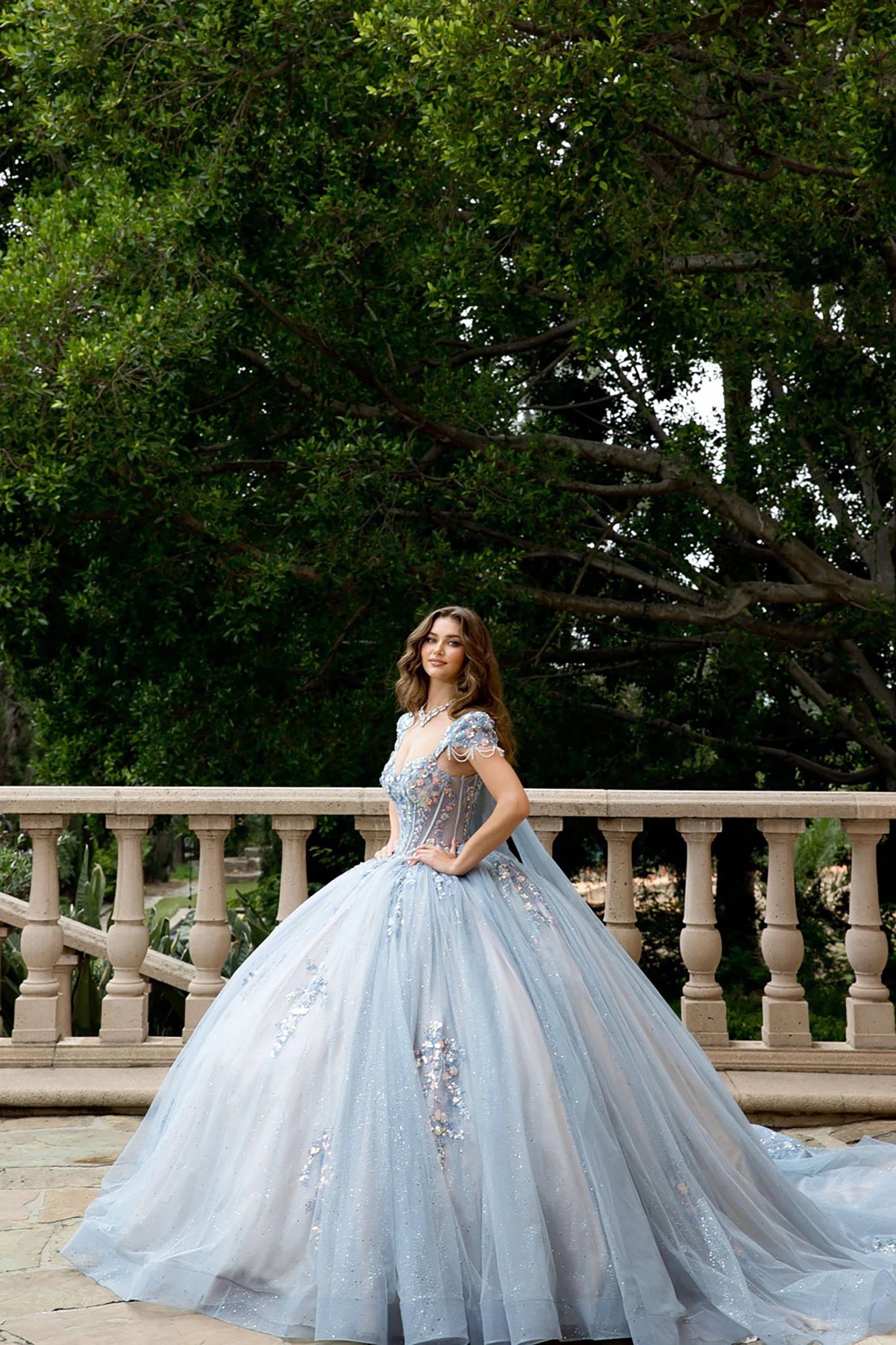Front view of a woman wearing a light blue quinceañera dress with corset bodice and embroidered details
