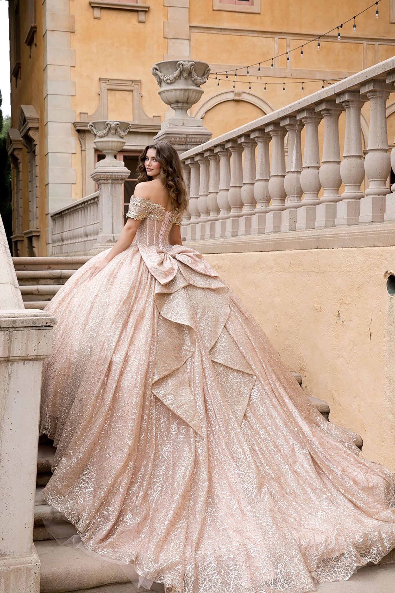 Woman in a sparkling gown standing on stone steps with classical architecture in the background