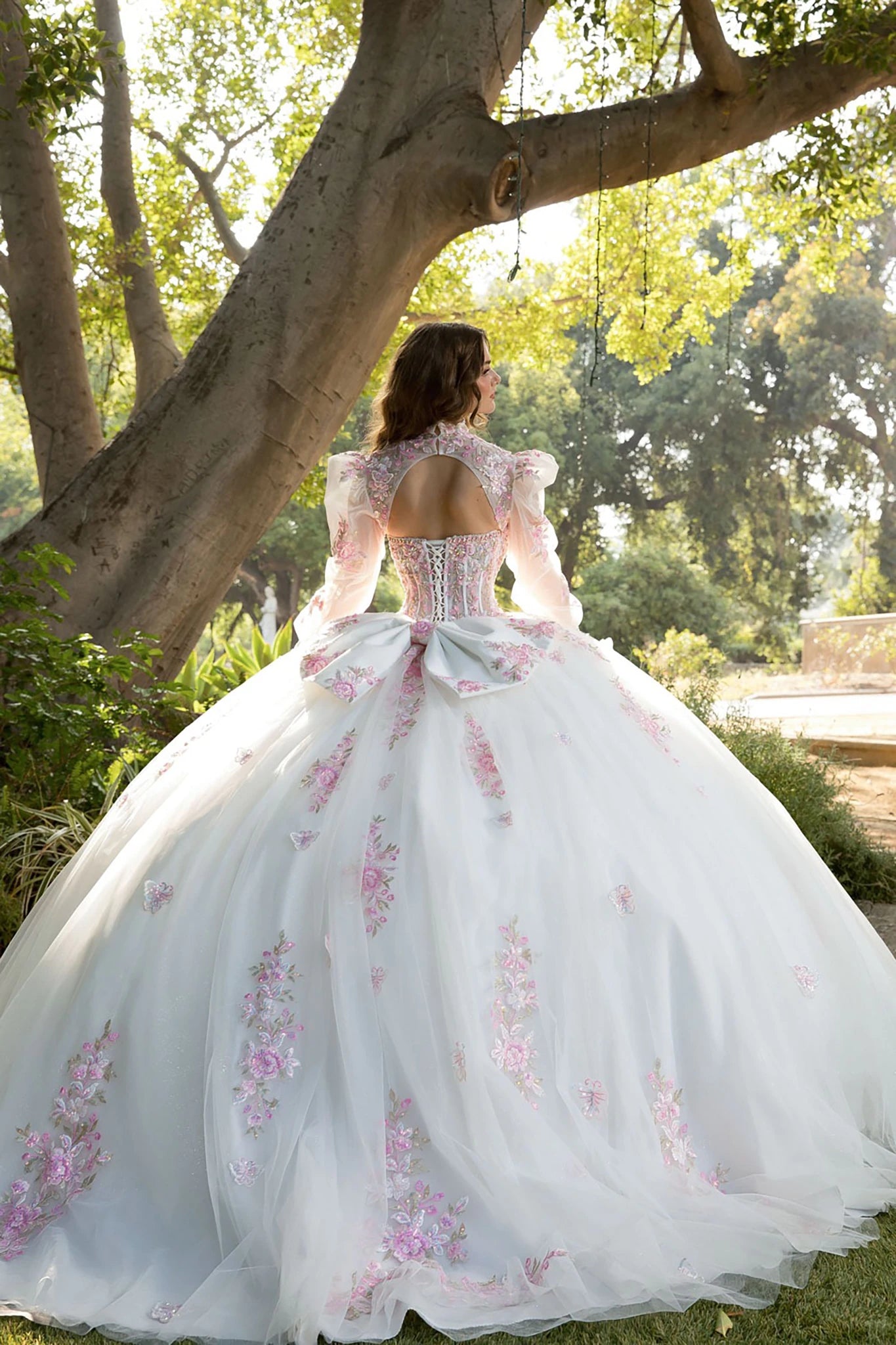 Back view of a woman wearing a floral quinceañera dress with corset bodice and embroidered details