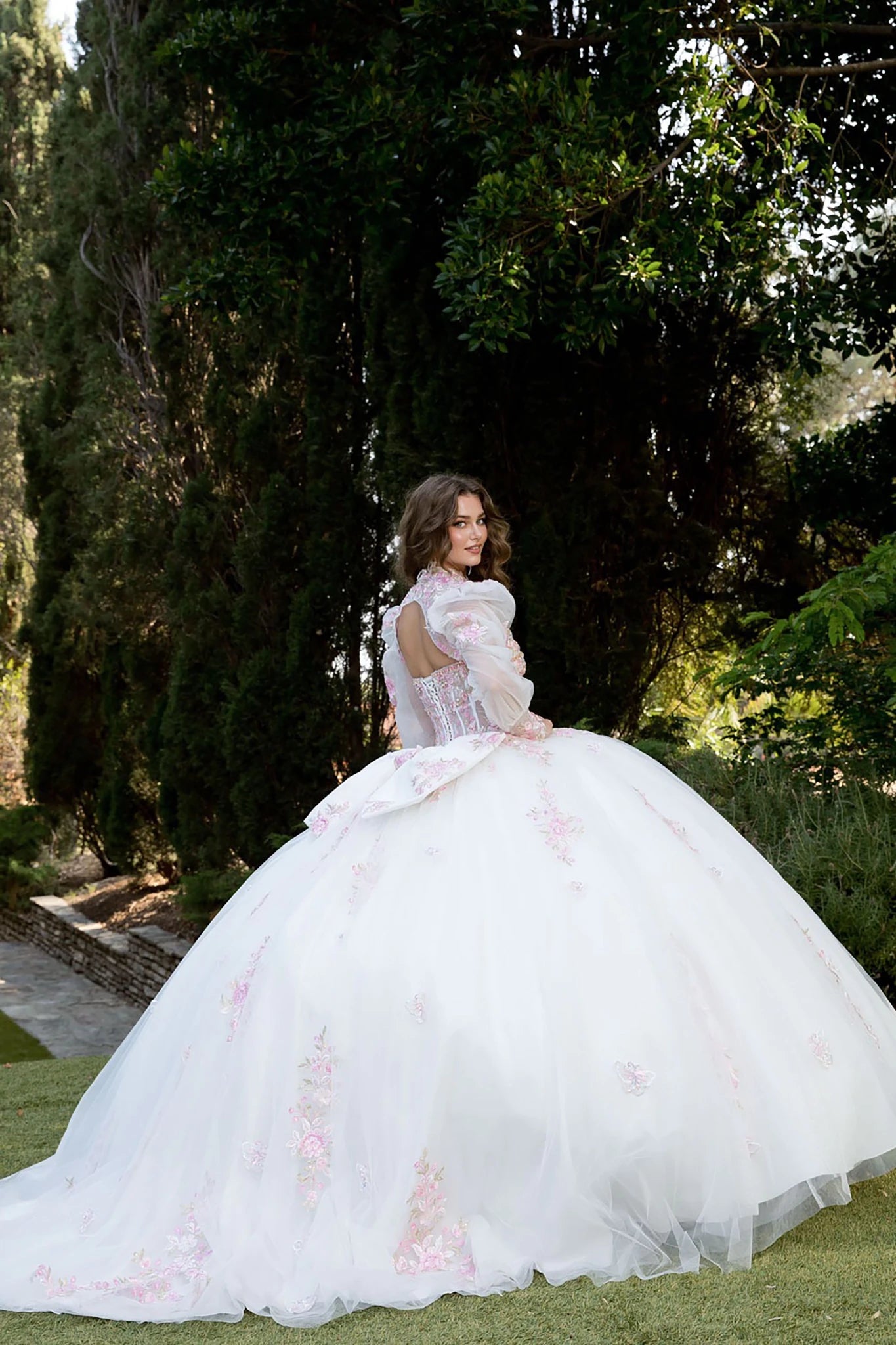 Back view of a woman wearing a white quinceañera dress with floral embroidery and corset bodice