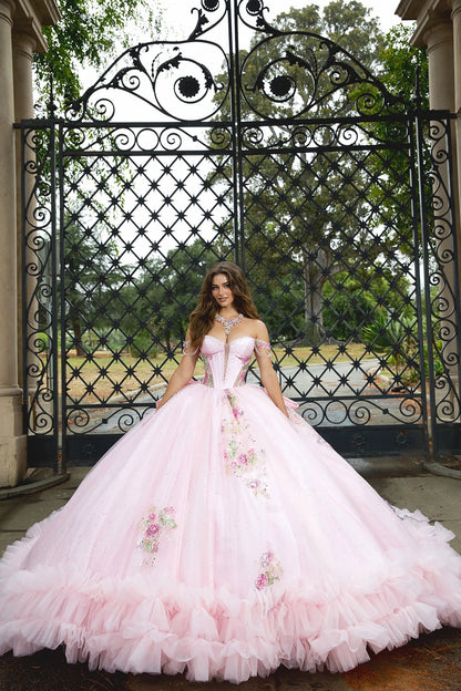 Woman in a pink floral dress standing in front of an ornate metal gate.