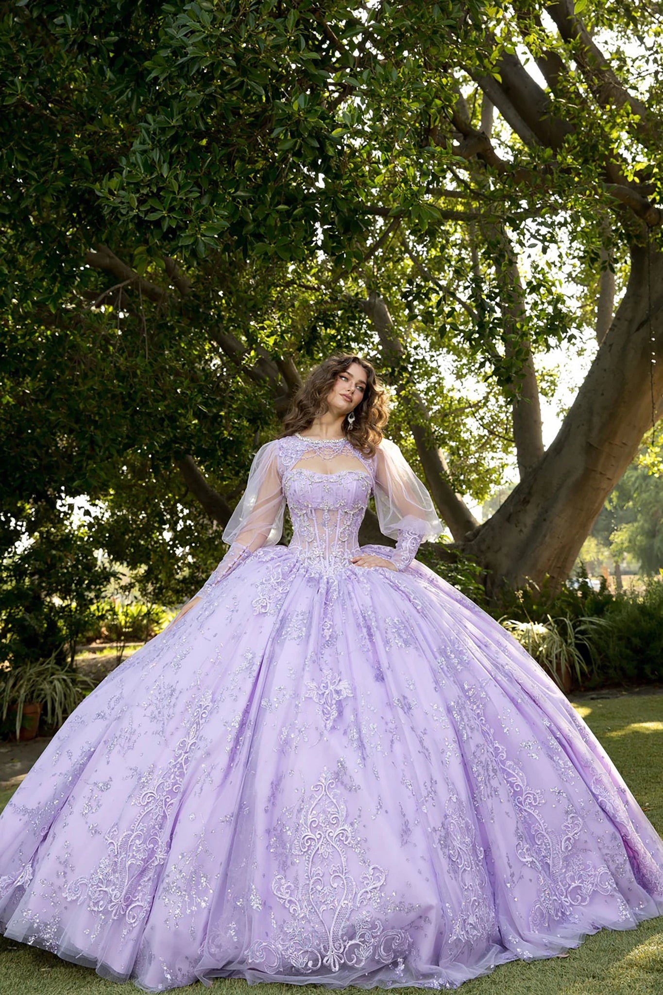 Front view of a woman wearing a lilac quinceañera dress with glitter tulle skirt and matching bolero jacket