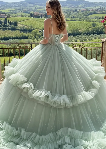 Back view of a sage green ballgown featuring a lace-up corset back, pearl-draped sleeves, and a voluminous tiered ruffled tulle skirt, overlooking a lush vineyard landscape.