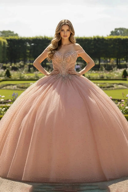 Rose Gold ballgown with a glittering tulle skirt and off-the-shoulder sweetheart bodice, decorated with shimmering crystal beadwork, shown in a manicured garden setting.