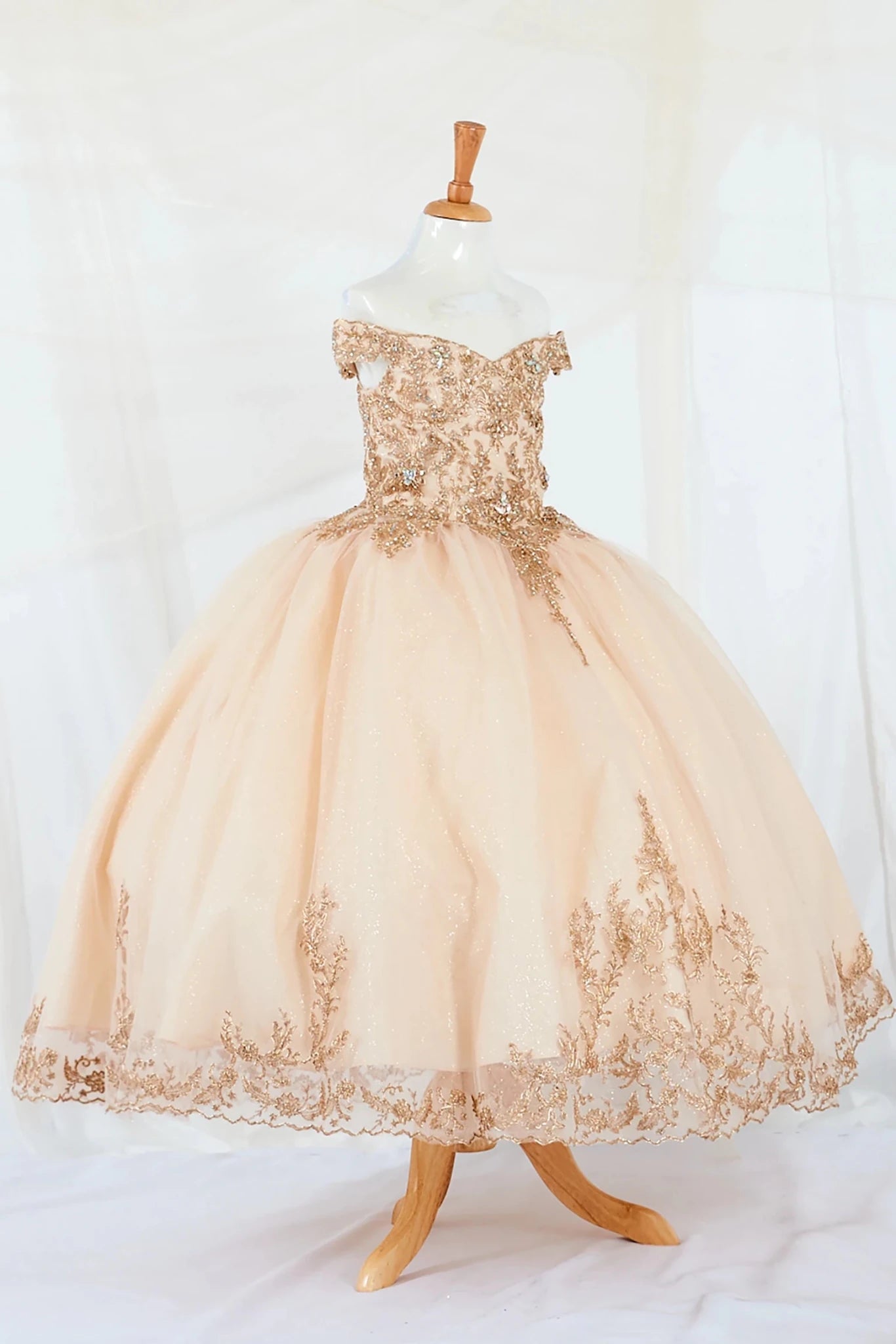 Gold- Beige off the shoulder kid lace ball gown dress on a mannequin against a white background