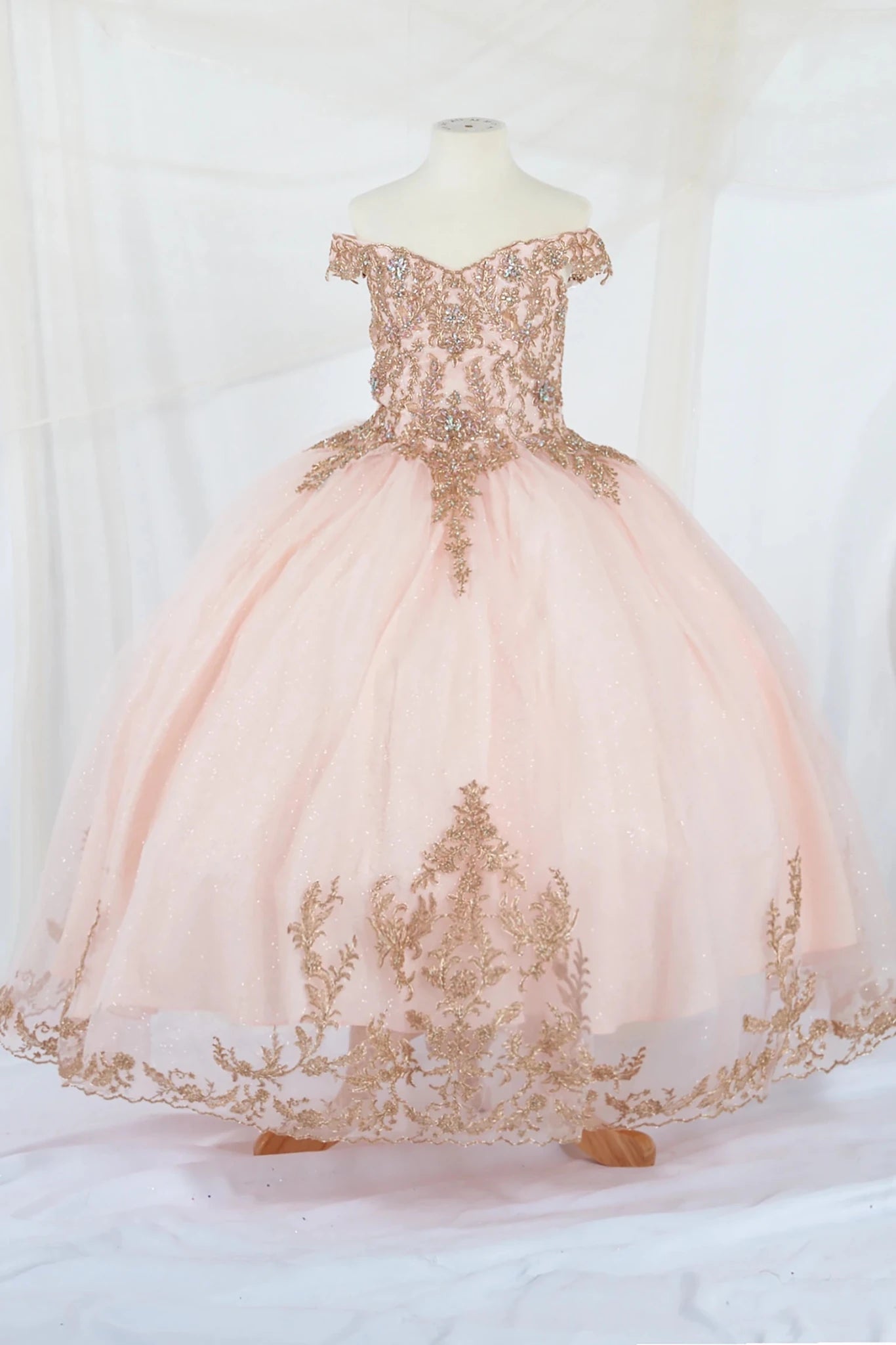 Pink off-shoulder mini quince dress with gold embroidery on a mannequin against a white background